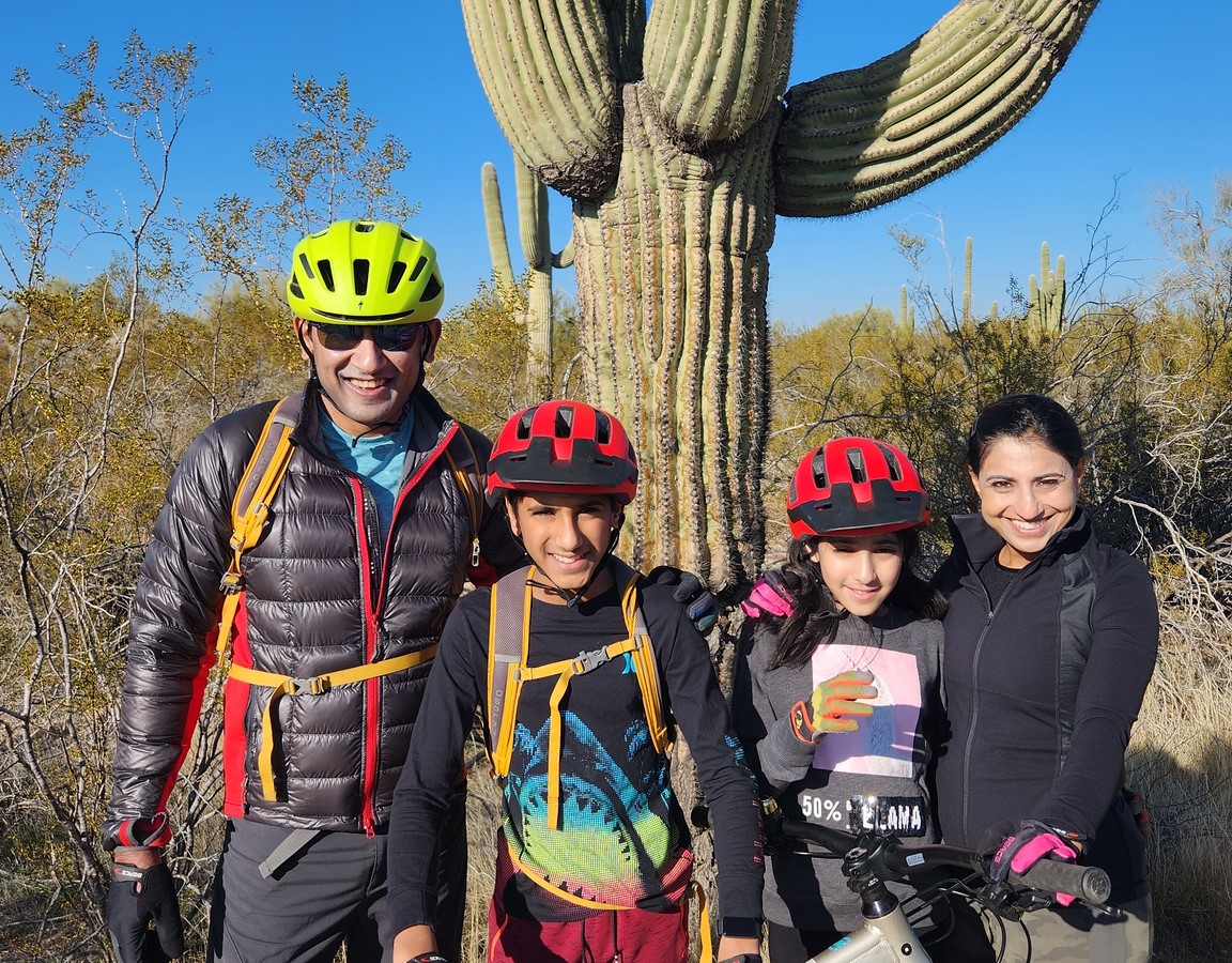 A family of four pauses to pose in front of the trademark of the old Southwest, a majestic Saguaro Cactus, during a Phoenix mountain bike tour with the Wild Bunch Desert Guides.