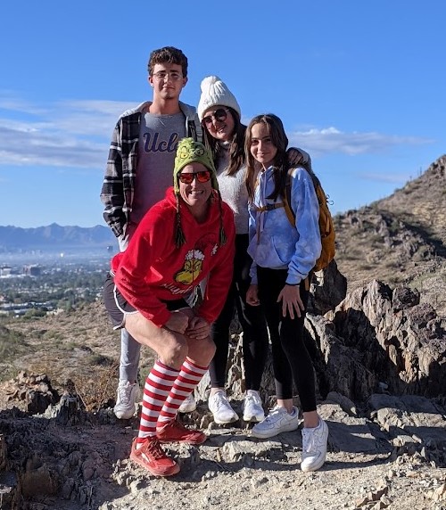 Laurel Darren (green hat), owner of the Wild Bunch Desert Guides, poses with a family during a holiday hike with a breathtaking view behind them.