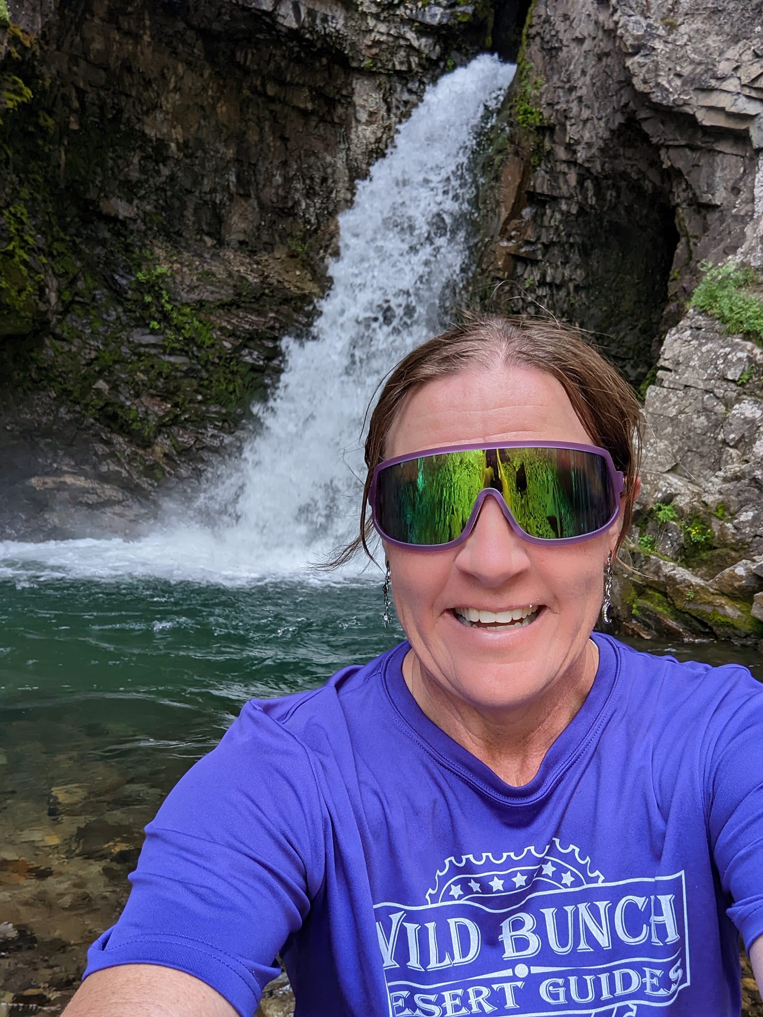 Laurel stops to admire the beauty of a cascading waterfall during one of the Wild Bunch's Colorado summer hiking tours.