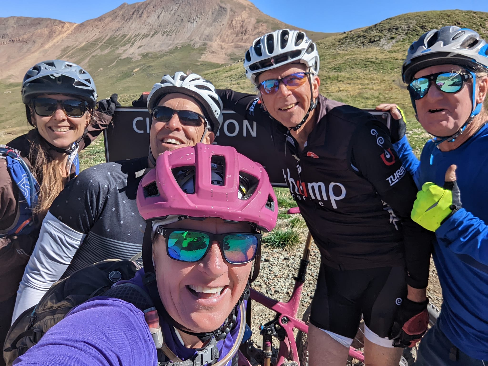 Wild Bunch Desert Guides owner Laurel Darren (front) is all smiles with a Colorado mountain bike tours group posing in front of the Cinnamon Pass sign in Lake City, Colo. Ms. Darren’s business, based in the Phoenix area of Arizona, offers guided hiking and biking during the summers in her remote vacation home tucked into the San Juan Mountains. (Courtesy Laurel Darren/Wild Bunch Desert Guides)