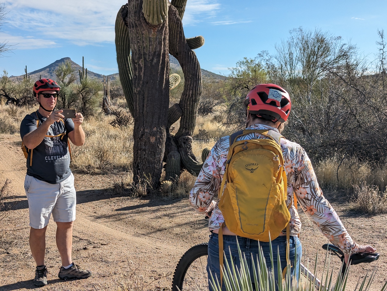 A husband pauses to take a picture of his wife posing in front of a picturesque backdrop on one of the Wild's Bunch's Phoenix mountain bike tours.