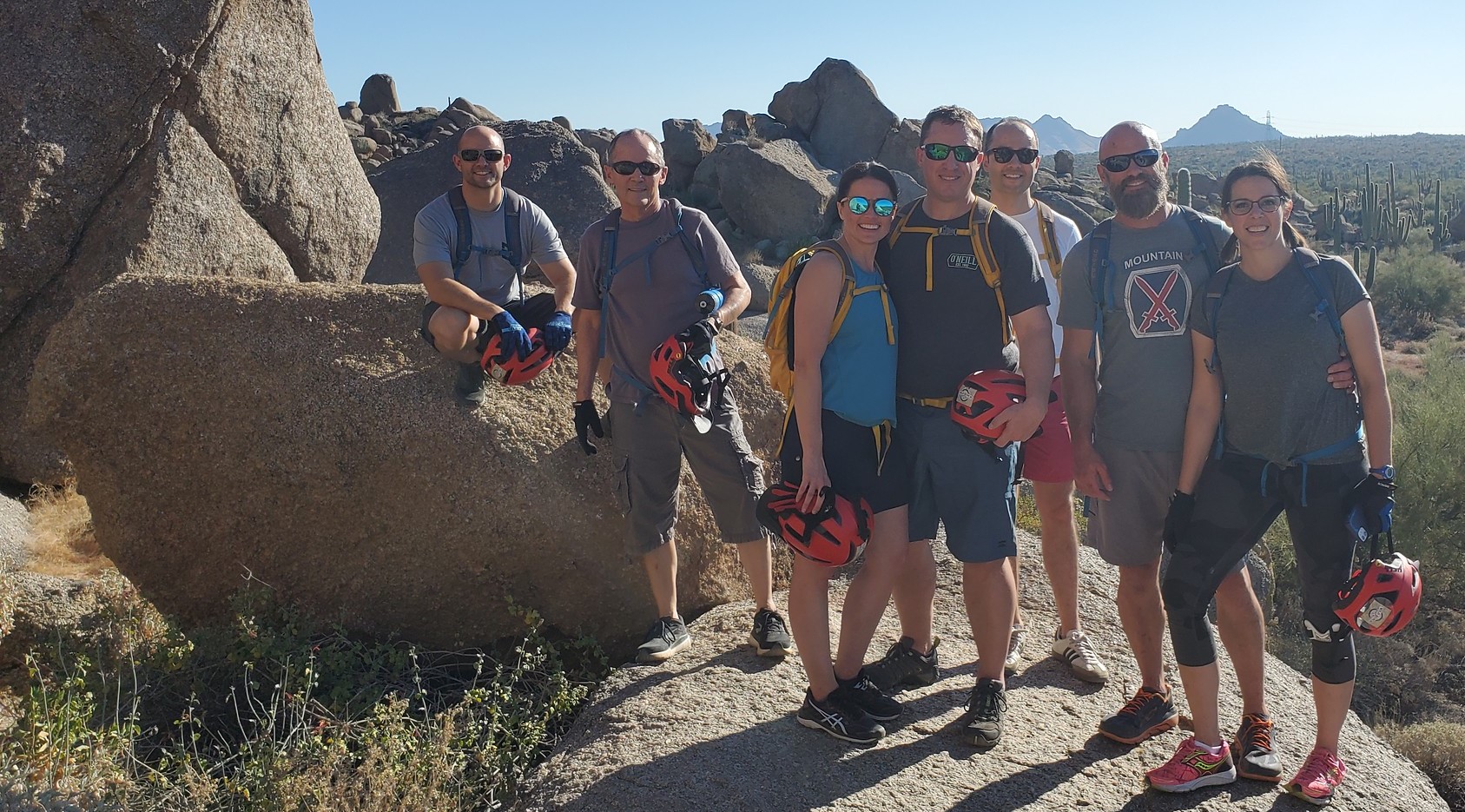 A Phoenix mountain biking group from the Wild Bunch Desert Guides pauses during an adventure tour to take a photo at an iconic Sonoran Desert rock formation.