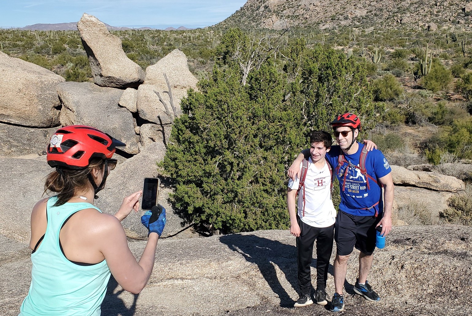 With a forest of cactus behind them, a father and son get their picture taken by their wife and mother during one of the Scottsdale mountain bike tours from the Wild Bunch Desert Guides.