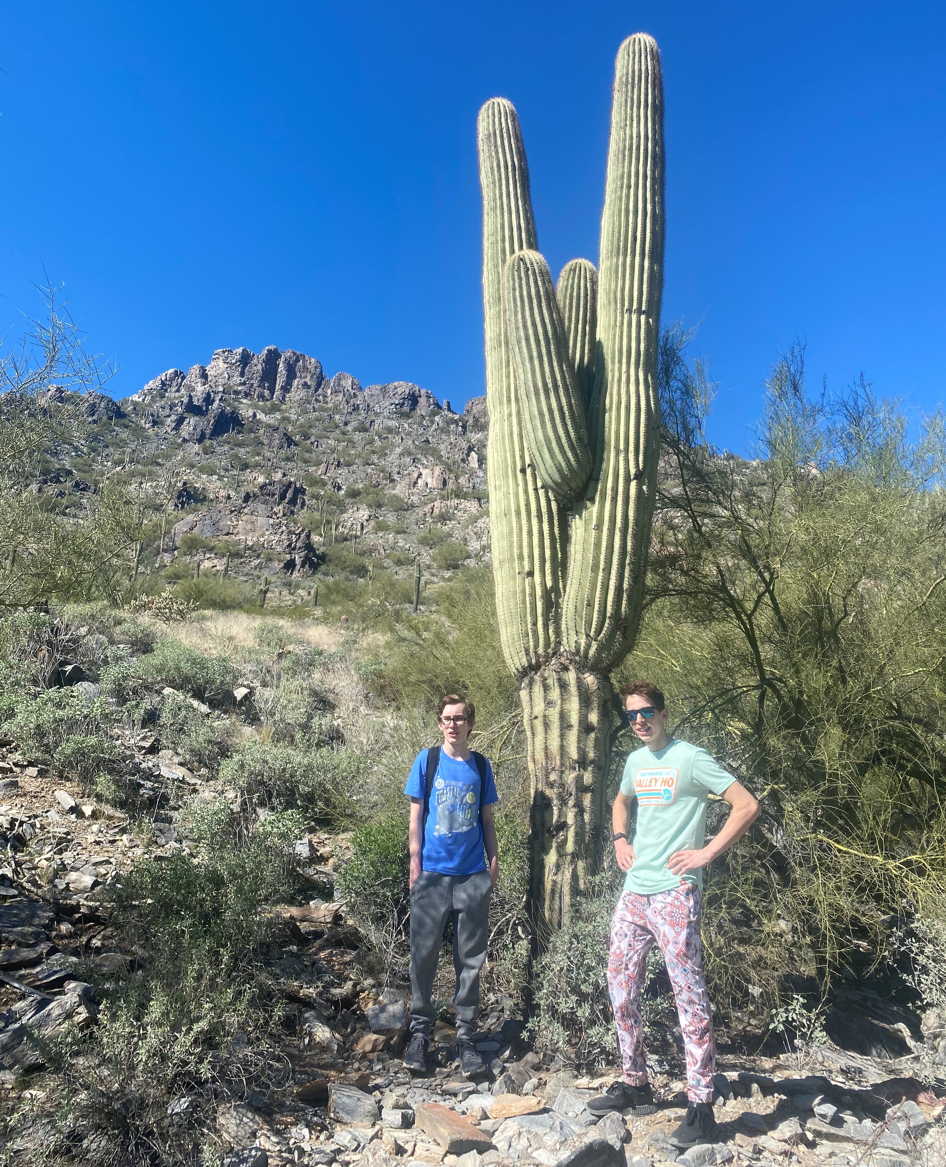 Ryan and Enzo pause to pose in front of a cactus during their hiking tour in Phoenix with the Wild Bunch Desert Guides.