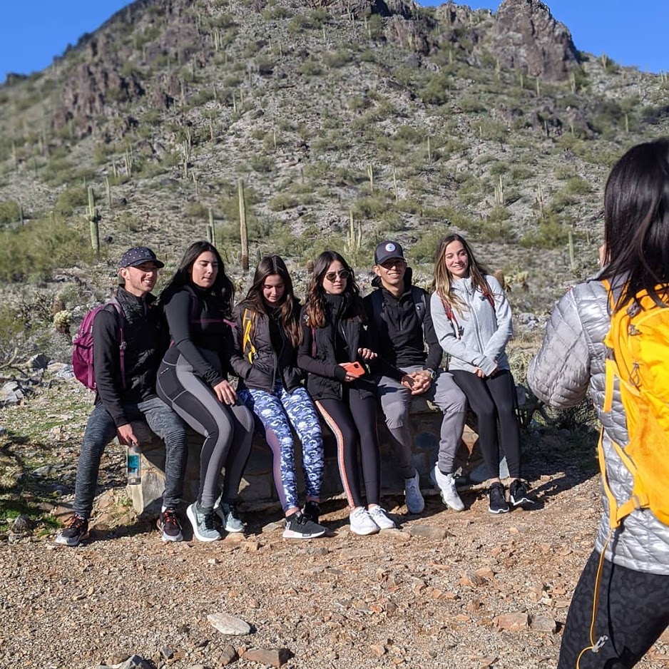 A Wild Bunch group of hikers stops to take a picture with the iconic Southwest scenery during a large group hike in Phoenix. 