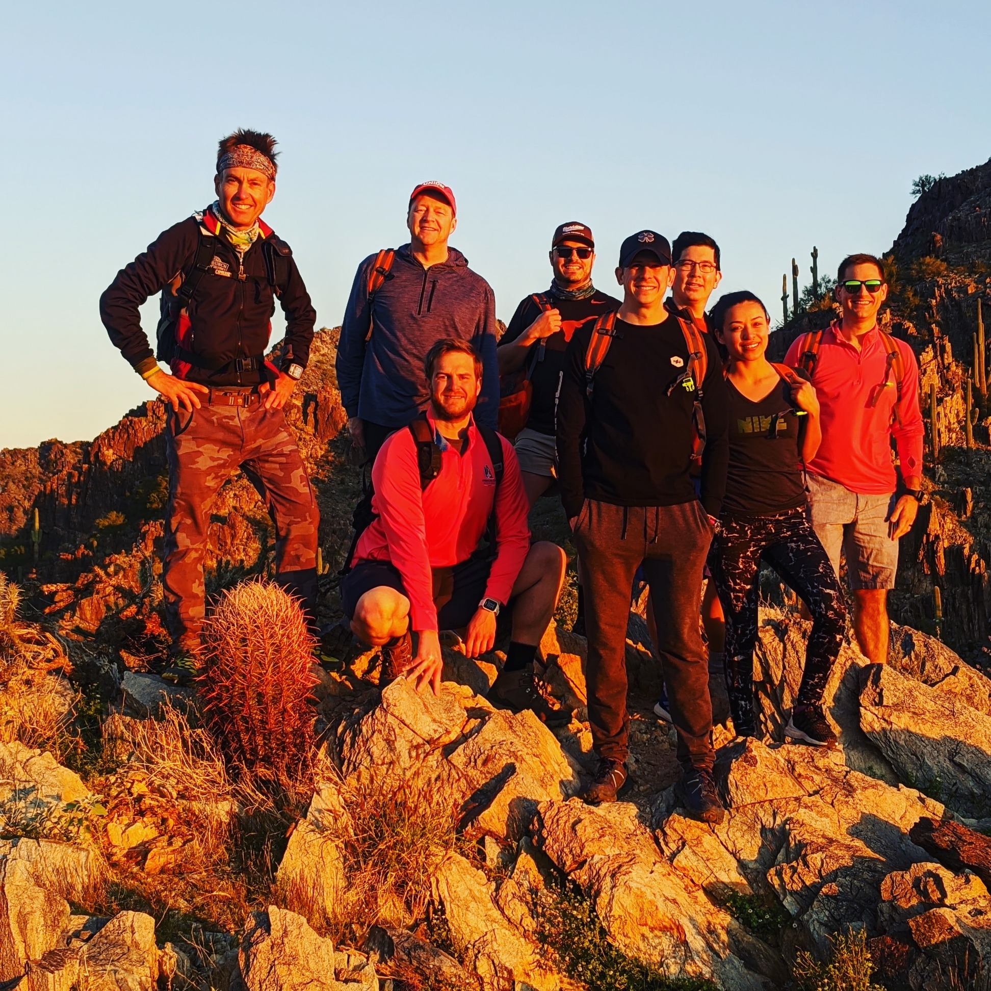 A group of eight hikers happily pose along the rocky terrain of another once-in-a-lifetime guided Phoenix hiking trip with the Wild Bunch Desert Guides.