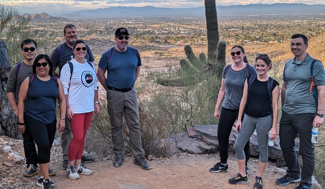 A Phoenix hiking tours group pauses for a memorable vacation picture with a breathtaking Sonoran Desert landscape behind them.