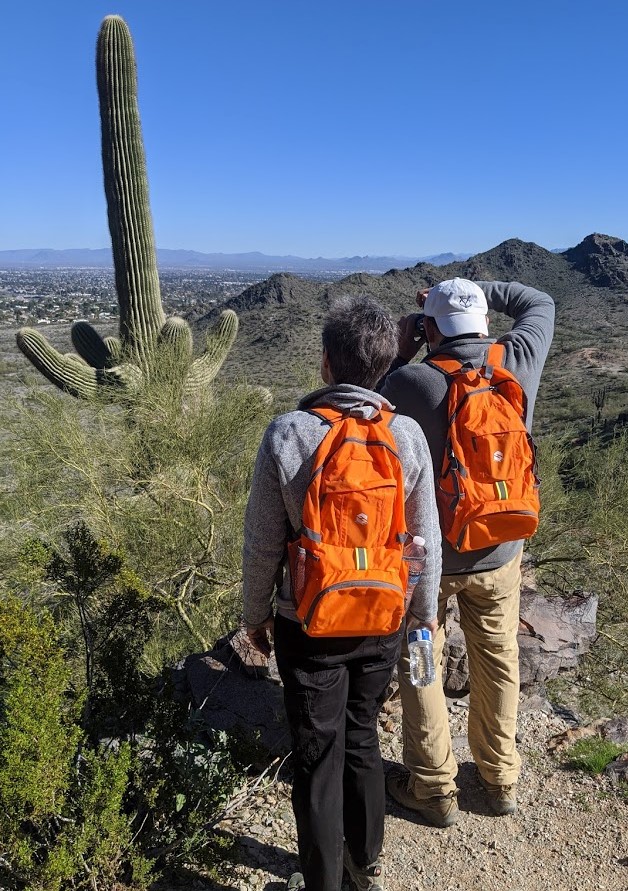 A couple of hikers pause together during a Wild Bunch Desert Guides hiking tour to take a picture of one of Arizona's iconic Saguaro cactuses.