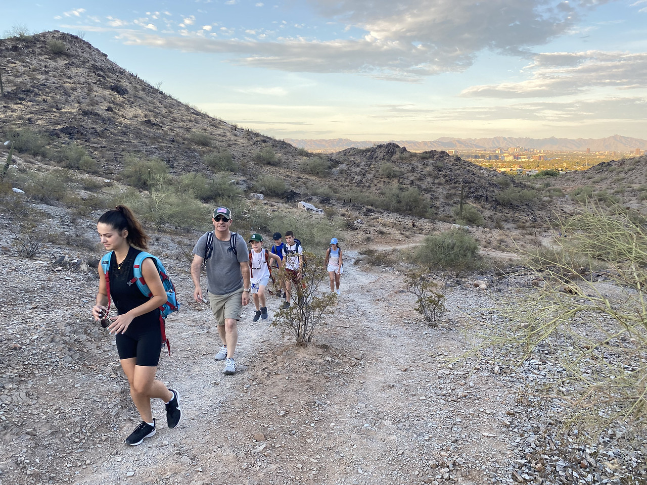 A family of six hikes up a hill with a mountainous backdrop behind them during a Wild Bunch adventure.