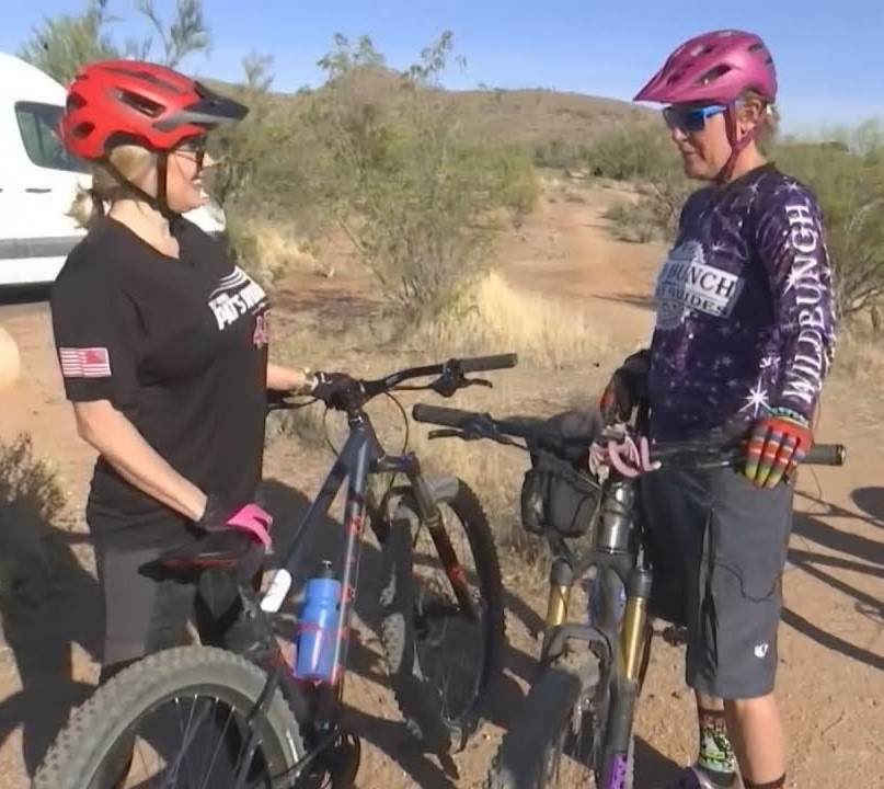 In this screen capture from KTVK-3TV, reporter Jaime Cerreta meets Wild Bunch owner Laurel Darren at the trail for their April 2021 mountain bike ride for a live "Jaime's Local Loves" segment on a newscast. (Courtesy WTVK-3TV)