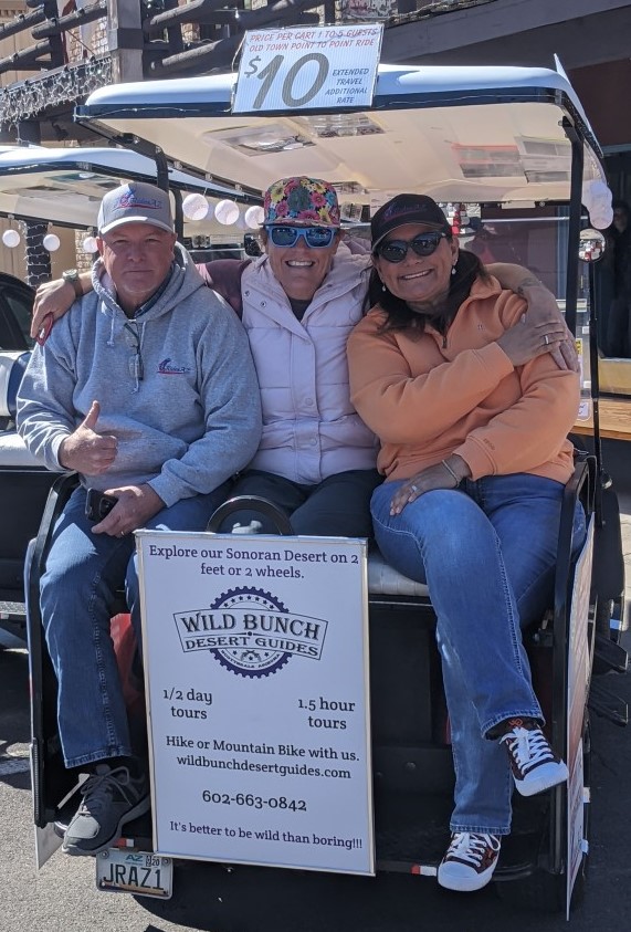 Wild Bunch owner Laurel Darren (center) poses on the back of a golf cart with JoyridesAZ owners Captain Kirk (left) and Monica (right).