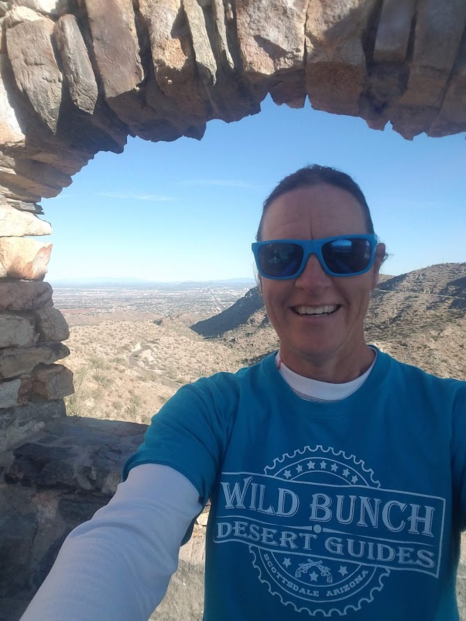 Wild Bunch Desert Guides owner Laurel Darren poses in a grotto rock formation during a guided hiking adventure in Phoenix. The beauty of the Sonoran Desert is behind her.