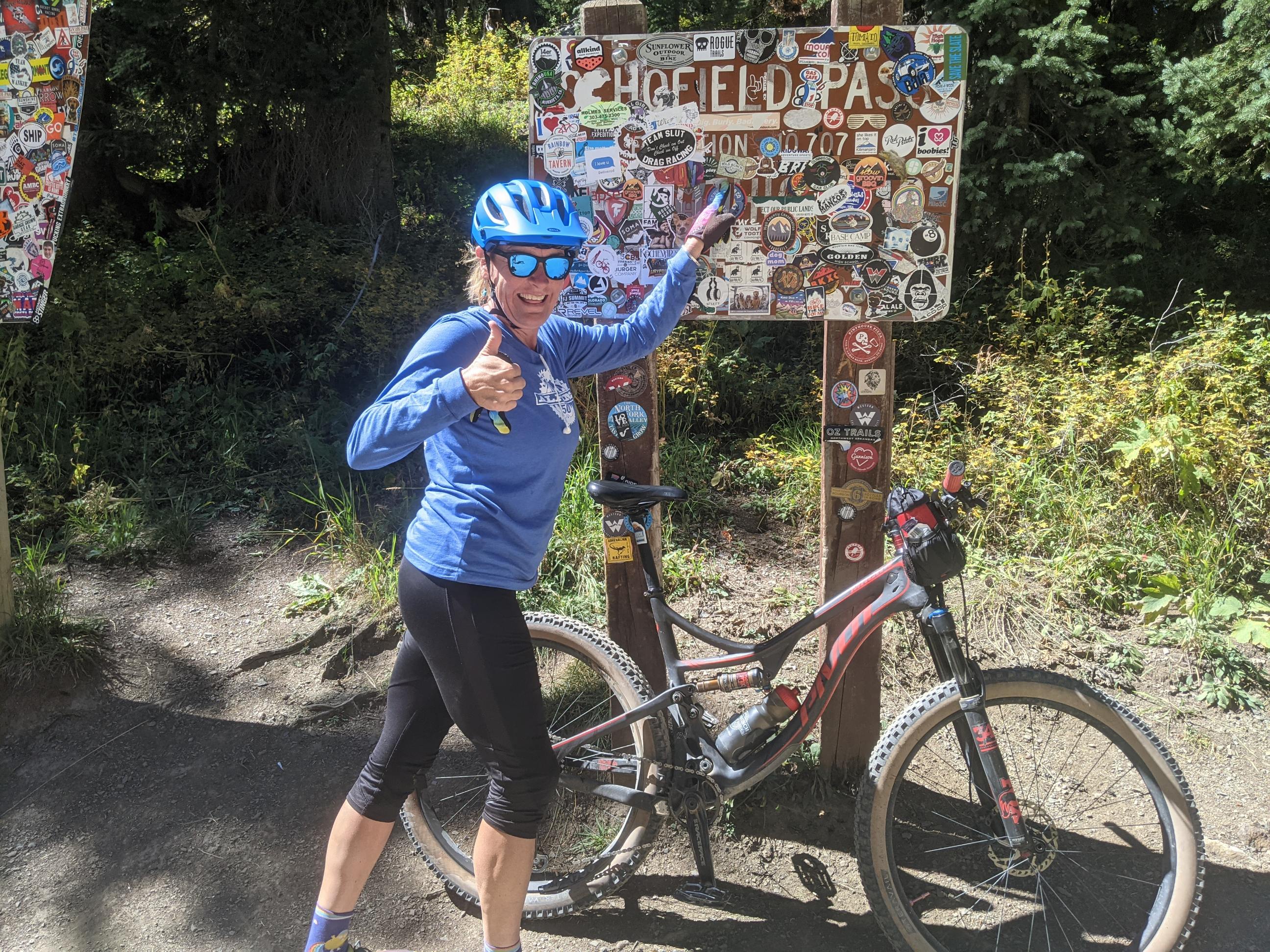 Laurel Darren is thumbs up excited while posing in front of a sign on Trail 401 in Crested Butte.