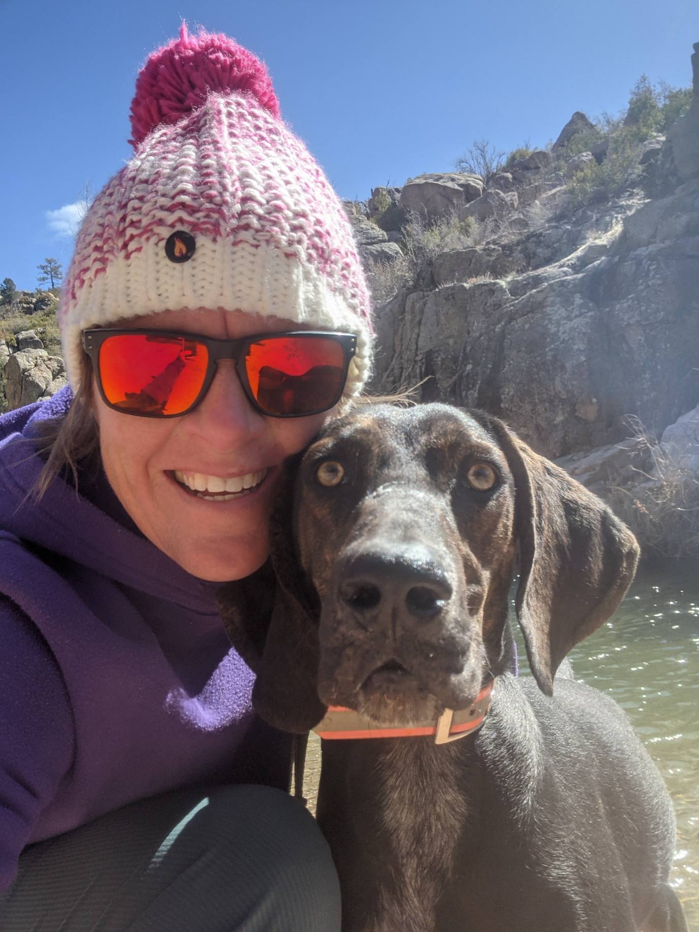 Laurel Darren, owner of the Wild Bunch Desert Guides, pauses during a hike to pose for a selfie with one of her two Plott Hounds, Waylon, with a picturesque backdrop behind them.