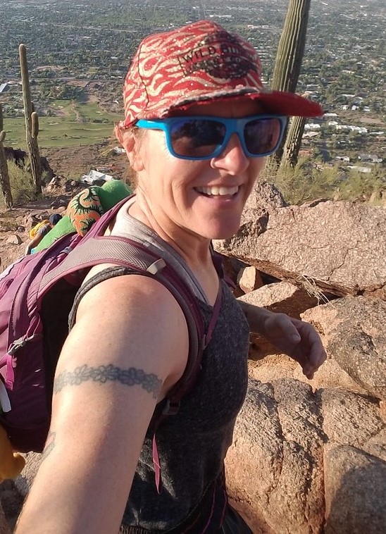 Laurel Darren, owner of Wild Bunch Desert Guides, flashes a wide smile with a breathtaking view as the backdrop during one of our guided Phoenix hiking tours.