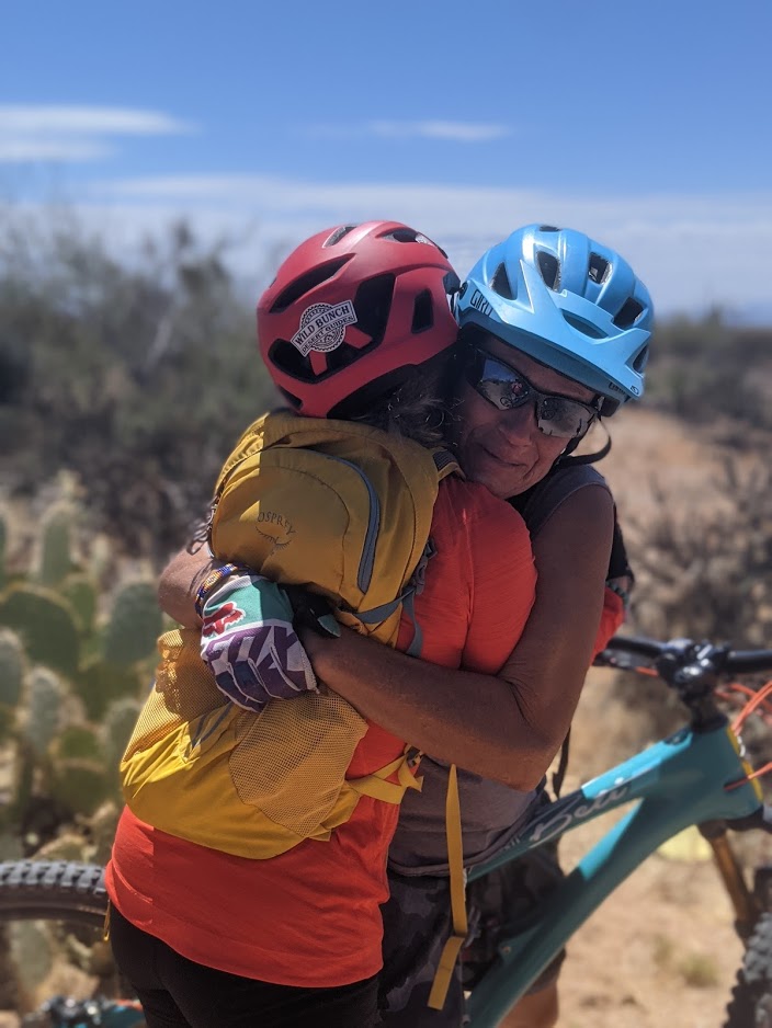 A Wild Bunch guide shares a huge hug with a guest after conquering a challenge on a Scottsdale mountain bike ride in the middle of Arizona's Sonoran Desert.