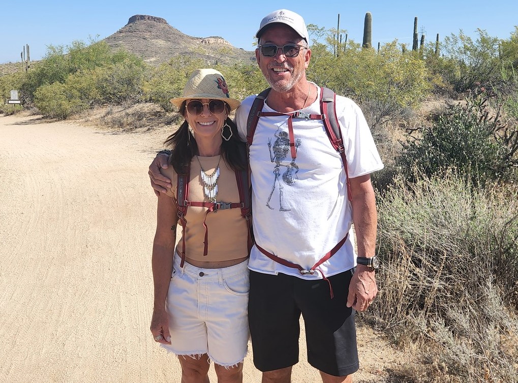 A man and wife pause for a picture along a scenic Sonoran Desert trail during one of our Phoenix hiking tours. Couples marking special occasions such as anniversaries or birthdays is a common sight on Phoenix adventure tours with the Wild Bunch Desert Guides.