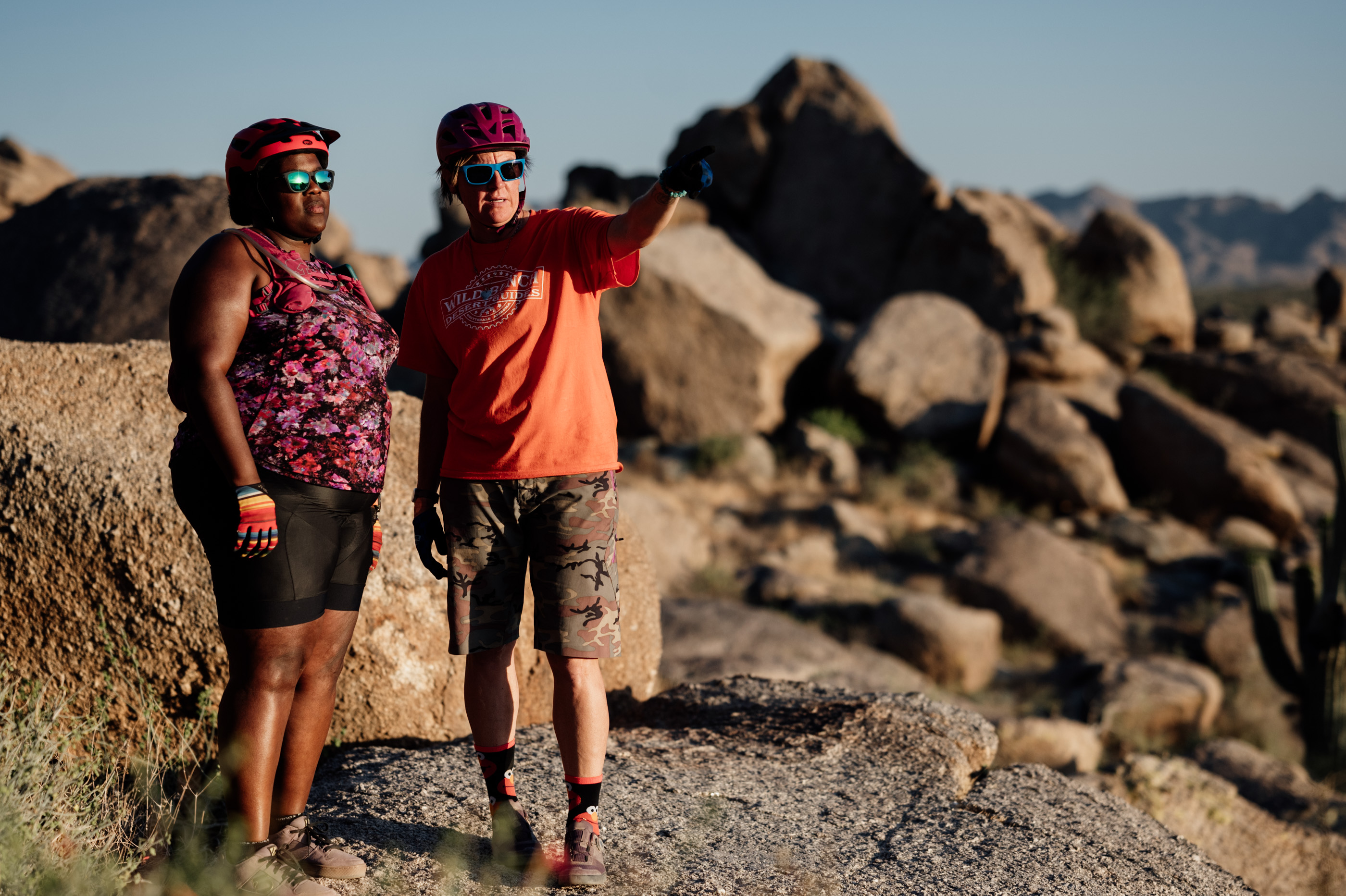 Laurel Darren (right) points out some scenery of interest to Mirna Valerio while they stand atop rocky scenery during a mountain bike ride.