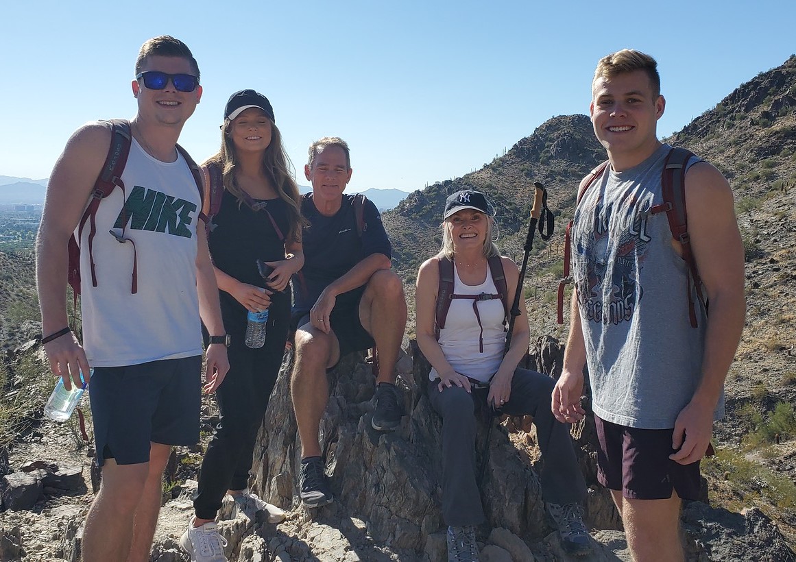 A family of five takes a break for a group picture with a breathtaking backdrop during one of the Phoenix hiking tours from the Wild Bunch Desert Guides.