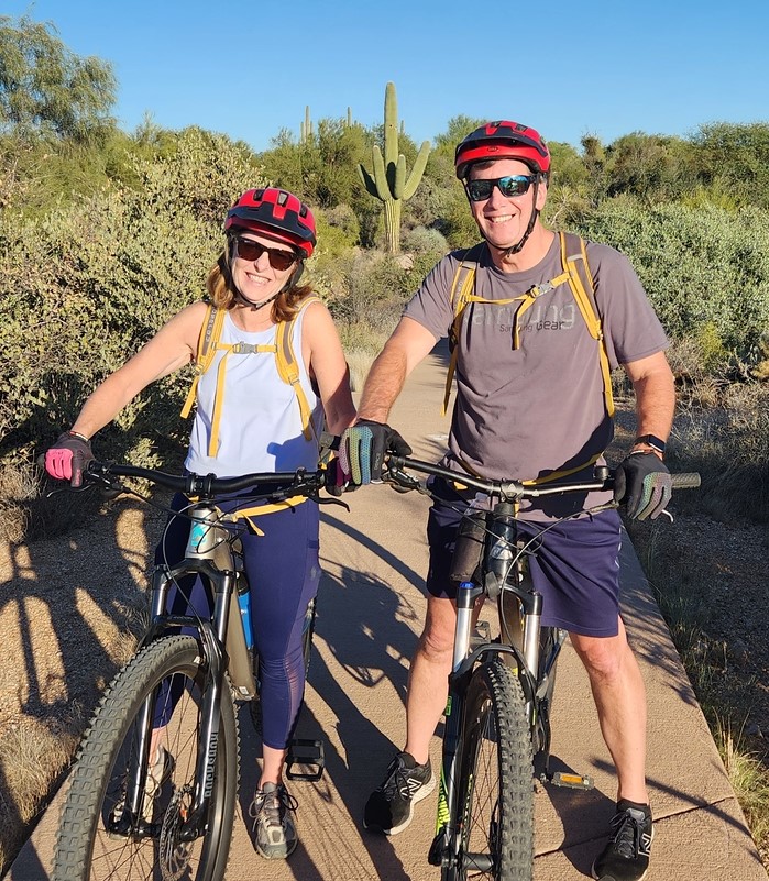 A couple pause for picture with Sonoran Desert flora behind them during one of the Phoenix mountain bike tours from Wild Bunch Desert Guides.