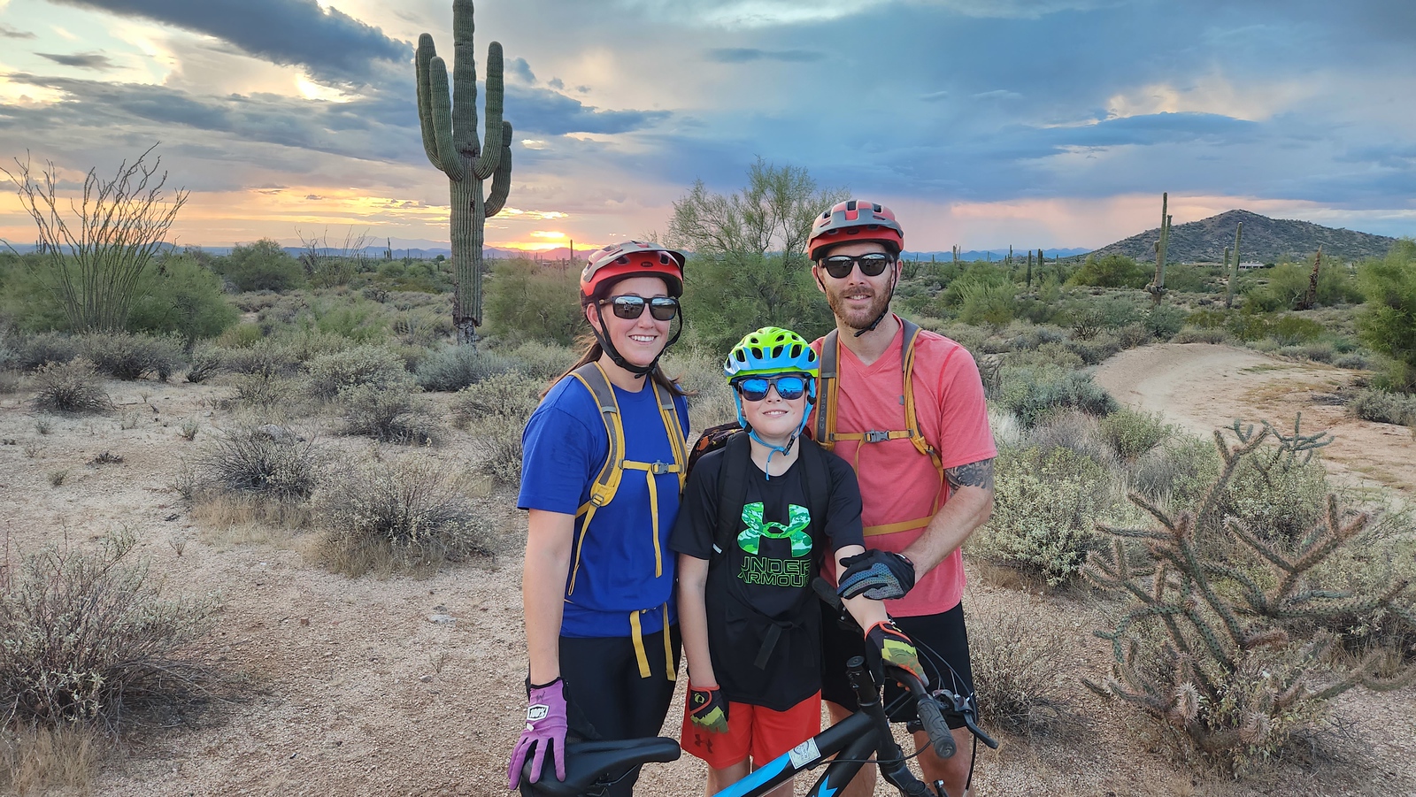 With an old southwestern backdrop and a gorgeous Arizona sunset on the horizon, a family of three pauses for a memorable vacation photo during one of the recent mountain bike tours from the Wild Bunch.