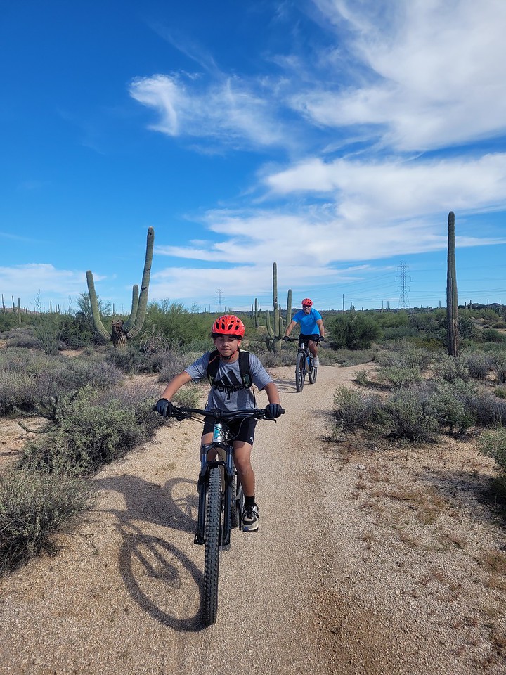 A father trails his smiling son during a Phoenix mountain bike tour with the Wild Bunch Desert Guides.