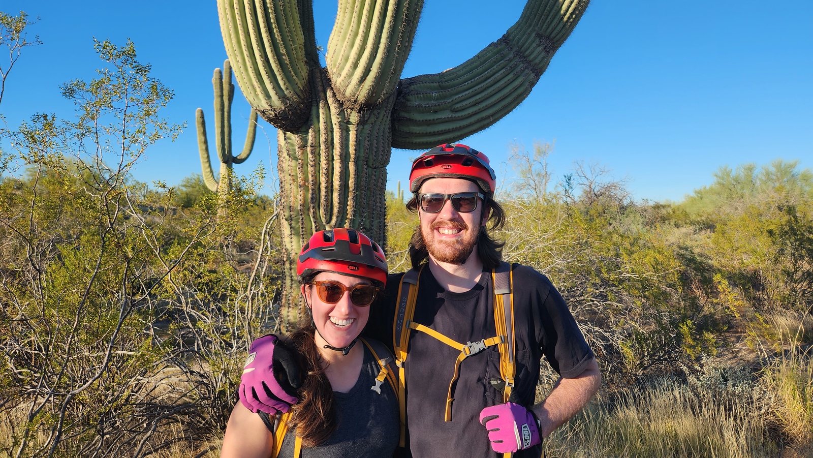 A happy pair pose with a Saguaro Cactus during one of the sunset Phoenix adventure tours with the Wild Bunch.