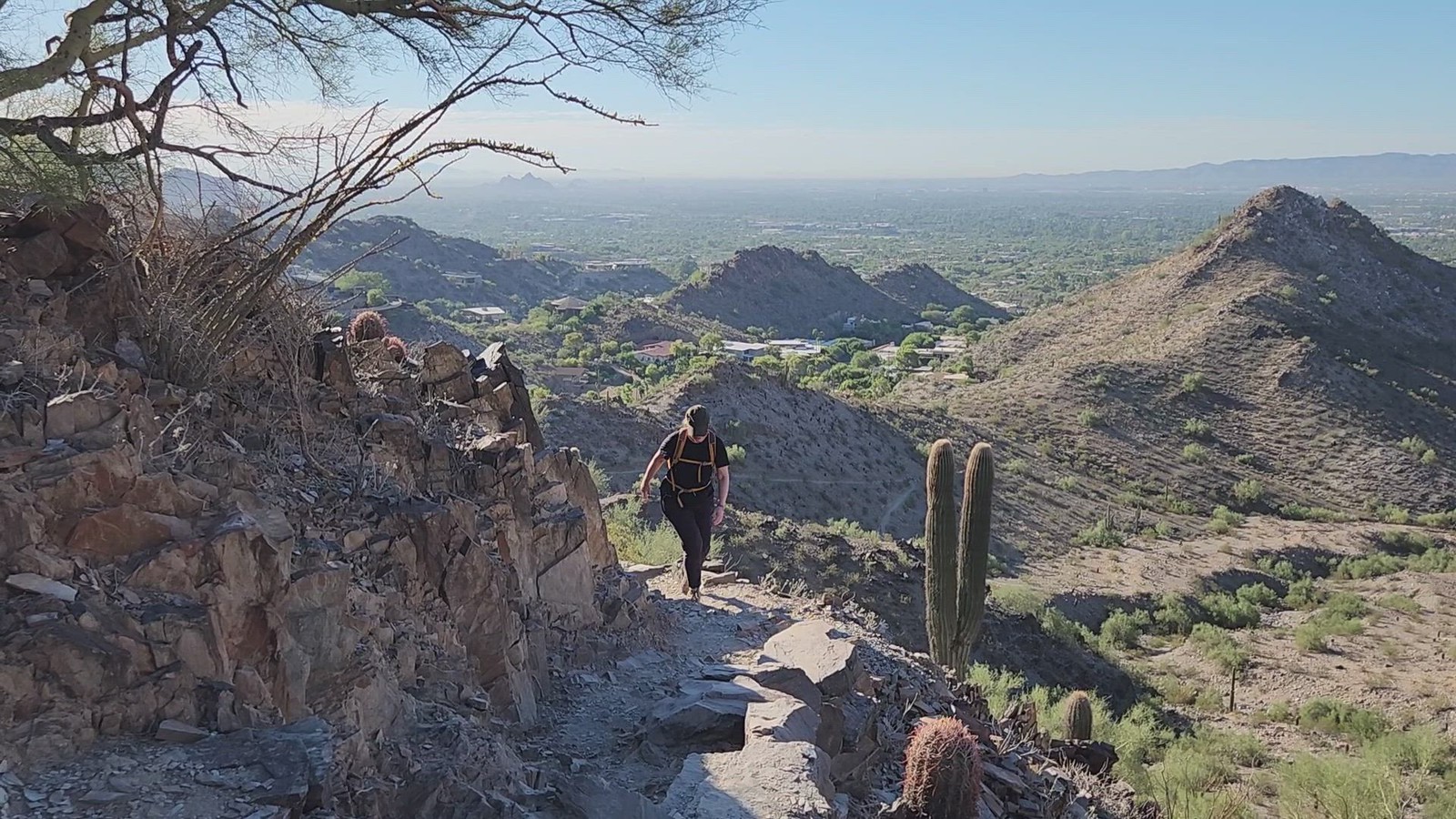 A female guest navigates a rocky trail surrounded by a scenic backdrop during one of the Phoenix hiking tours from the Wild Bunch Desert Guides.