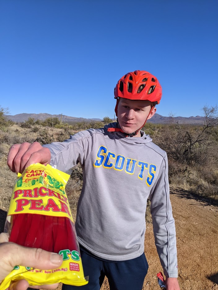 A man accepts the offering of Prickly Pear licorice for a snack break during a Wild Bunch hike.