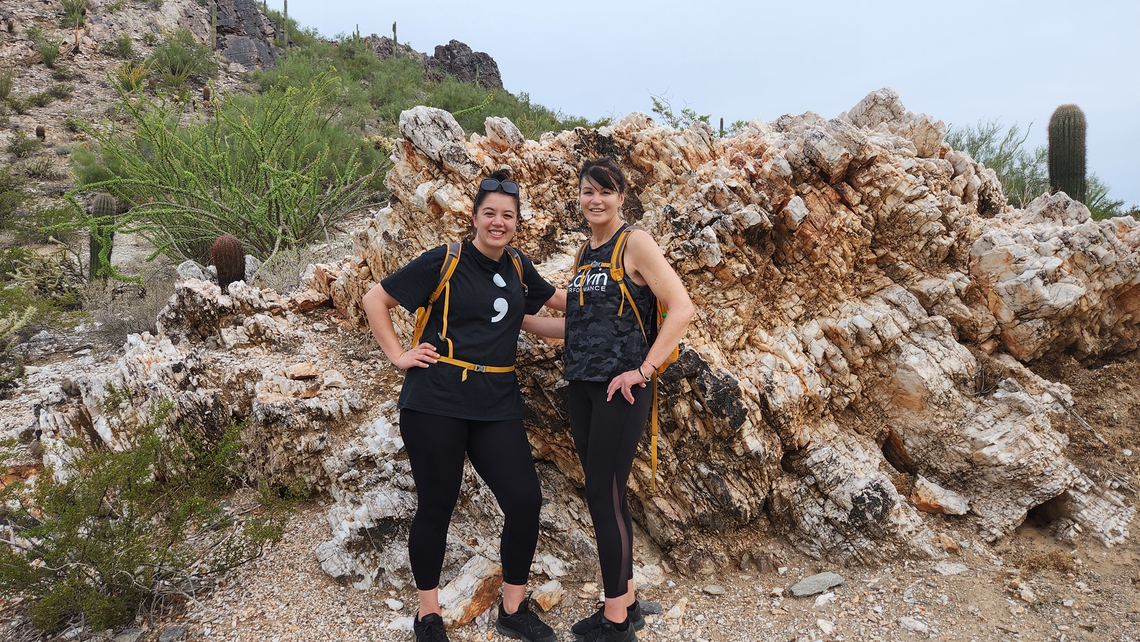 A couple of friends all smiles posing in front of a rock formation during one of the recent Phoenix hiking tours from the Wild Bunch.