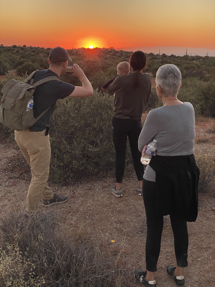 A three-generation family -- a grand mother, two parents and a baby -- soak in the sunshine of a gorgeous Arizona sunset during one of the Phoenix hiking tours from the Wild Bunch Desert Guides.