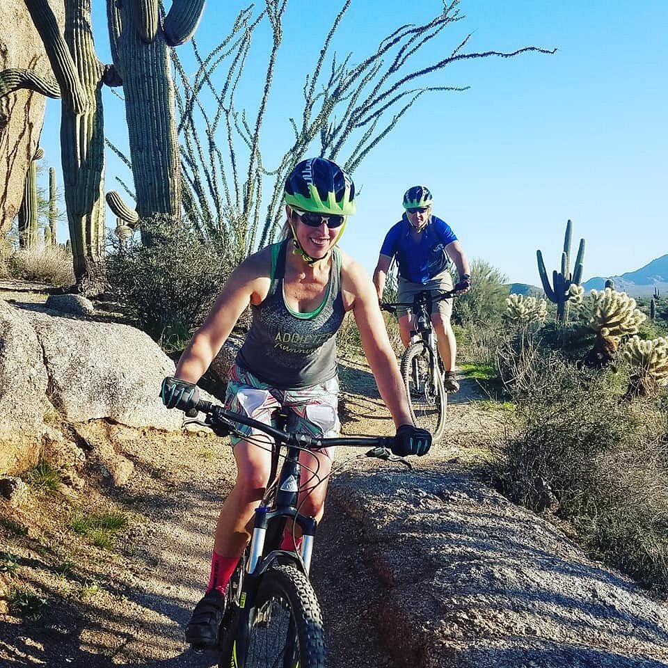 With a variety of cactus along the trail, a wife and husband enjoy a Phoenix mountain bike adventure together with the Wild Bunch.