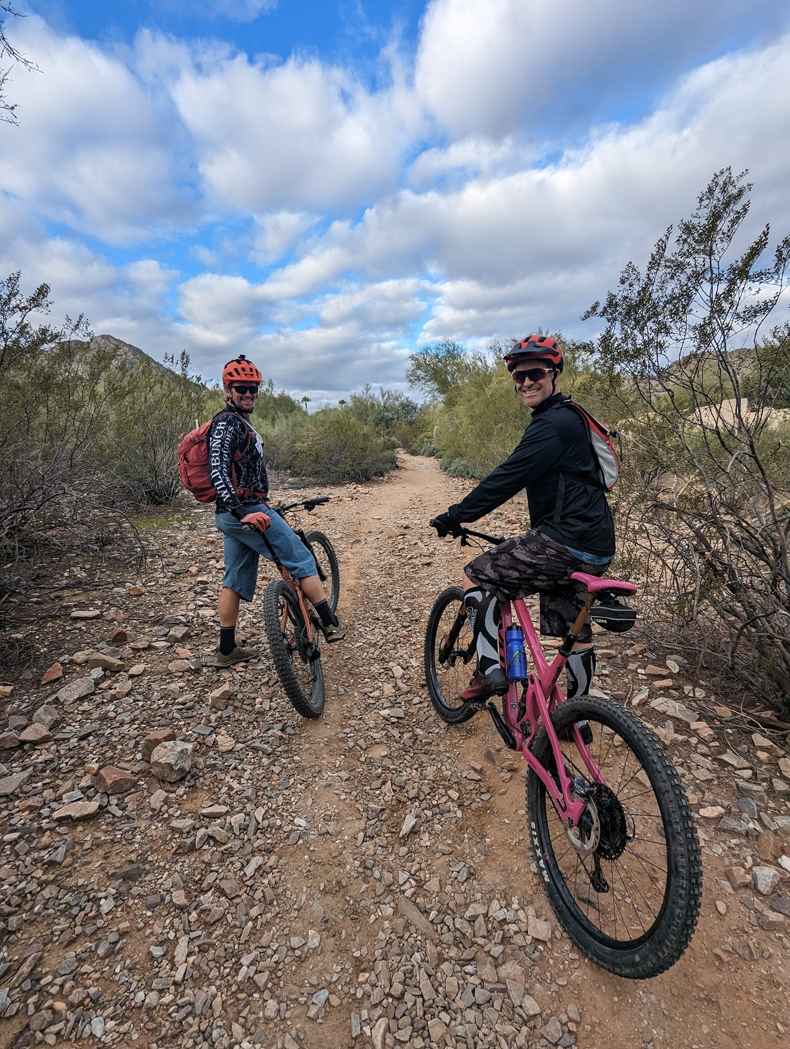 A pair of cyclists on a Phoenix mountain bike tour peer back at the camera during a Wild Bunch Desert Guides adventure.