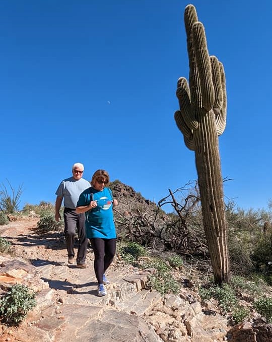 A couple descends a rocky downhill past the Old Southwest trademark of a Saguaro Cactus during a Phoenix hiking tour with the Wild Bunch.